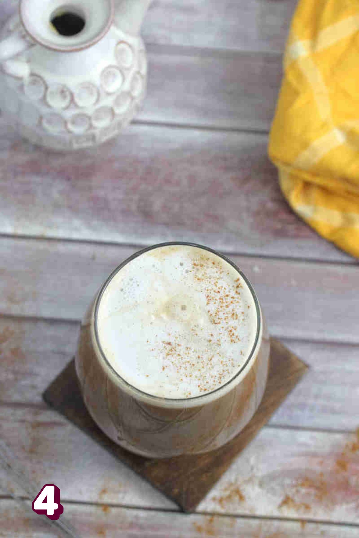 Maple protein latte in a glass with frothed milk on top.