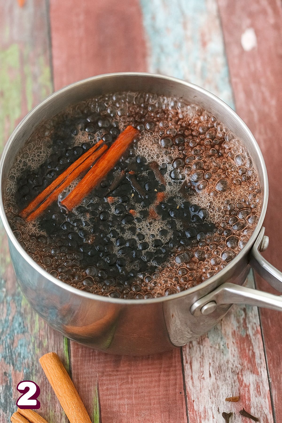 Elderberry cough syrup with cinnamon in a small pot boiling.