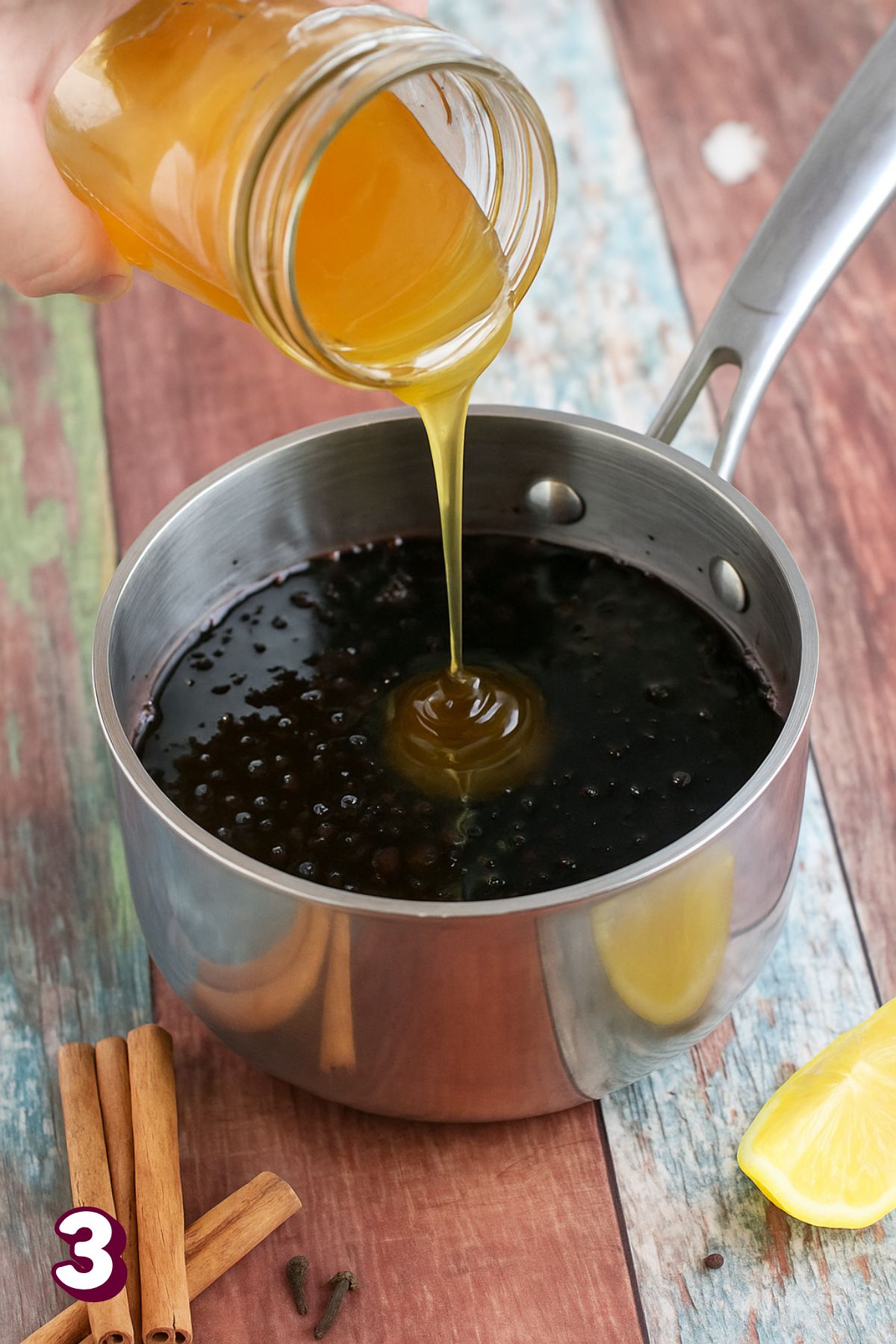 Honey being poured into elderberry syrup in a pot.