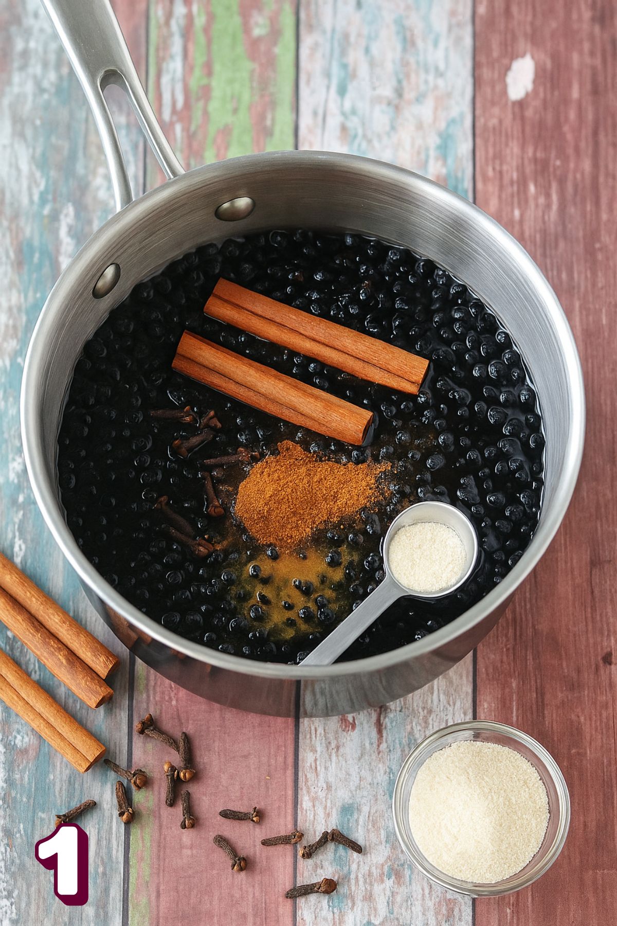 Elderberries, cinnamon, and spices in a small pot.