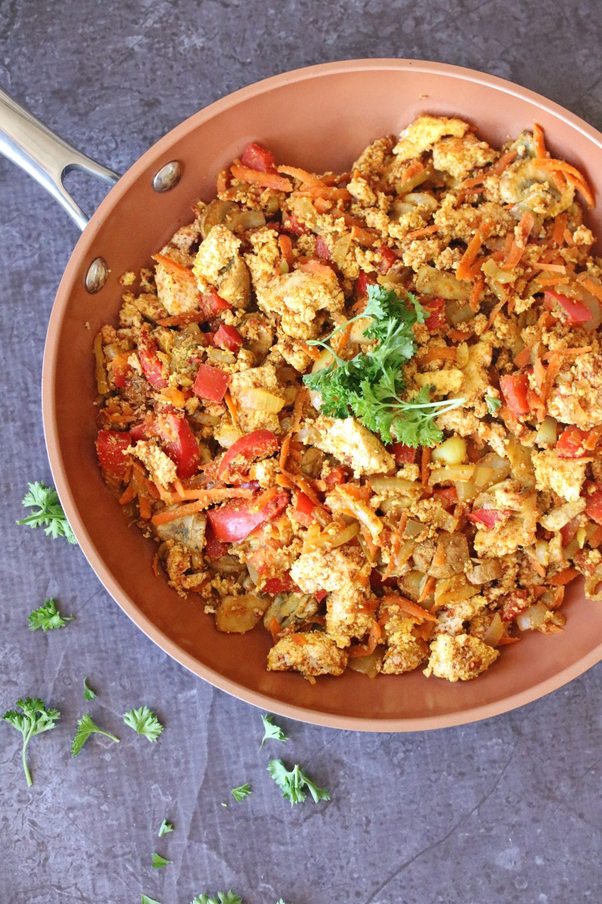 Tofu, red peppers, and carrots in a pan with parsley.