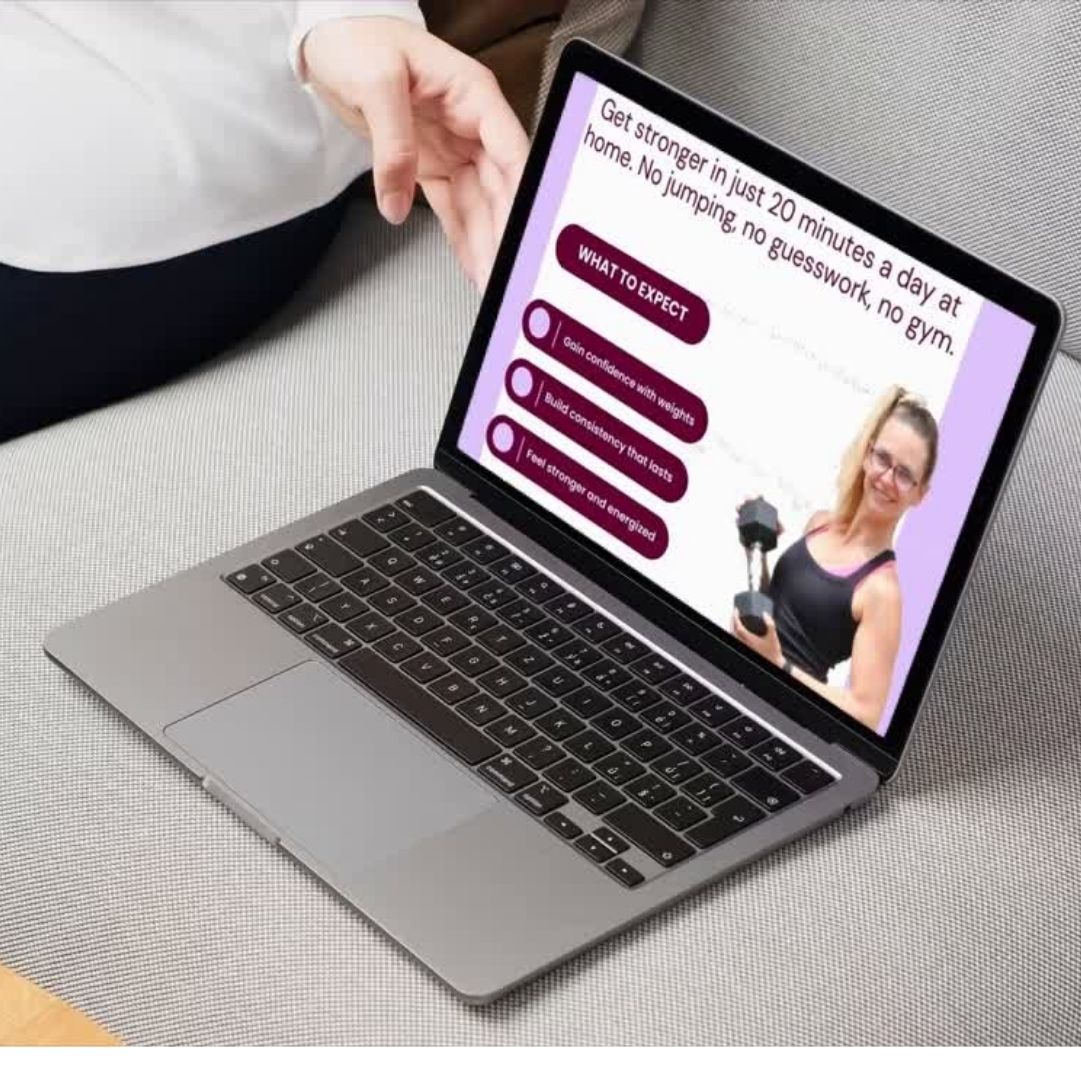 Computer on a couch with hand holding, on the computer is a woman holding a dumbbell.