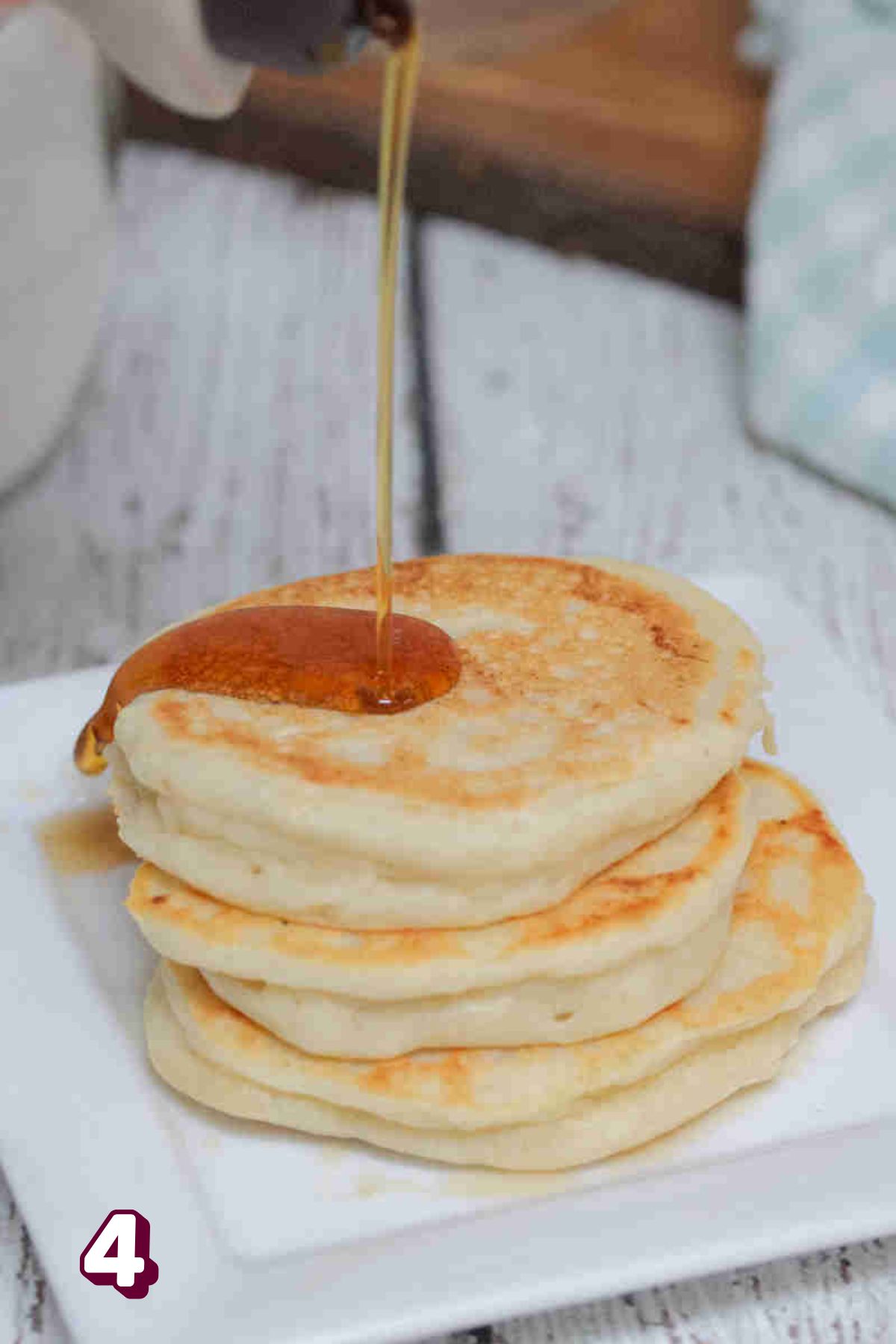 A stack of pancakes with maple syrup on a plate.