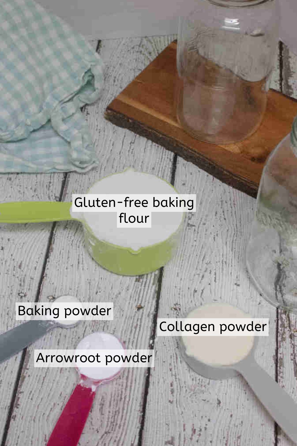 Baking powder, baking flour, collagen powder, and arrowroot powder in measuring cups and spoons.