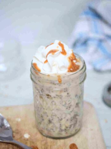 Mason jar with overnight protein powder oats topped with whipped cream and sauce.