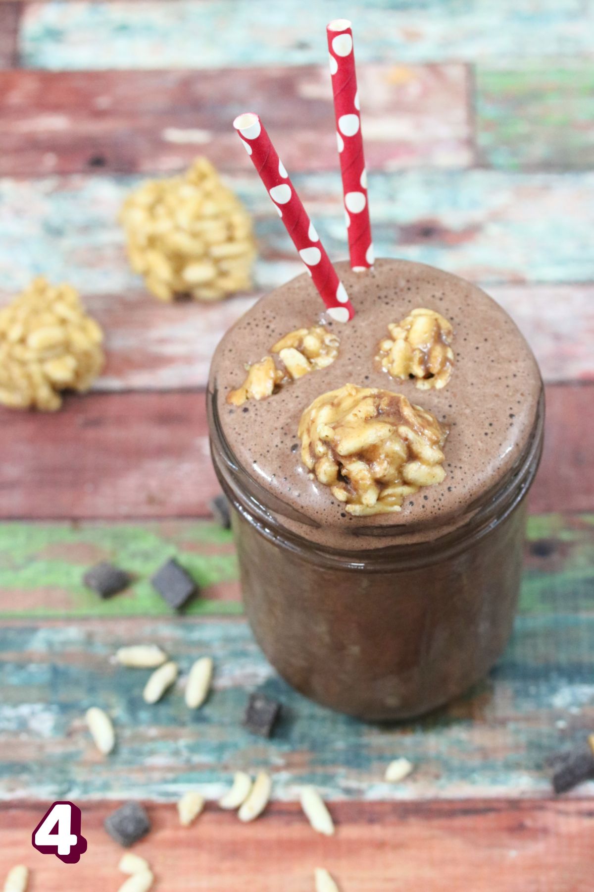 Chocolate peanut butter shake in a mason jar with peanut butter balls on top and red straws.