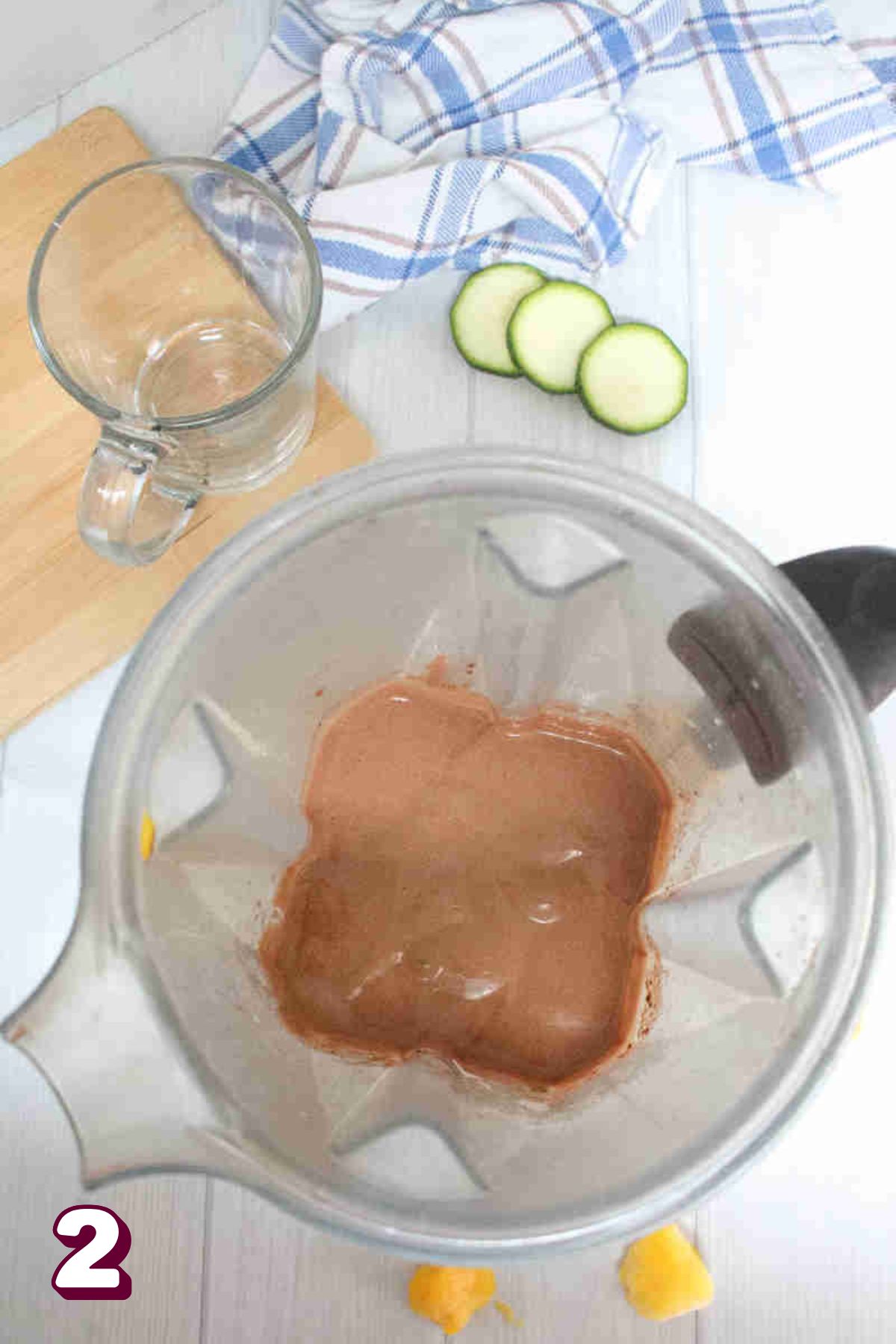 Chocolate smoothie in a blender with ingredients around it.