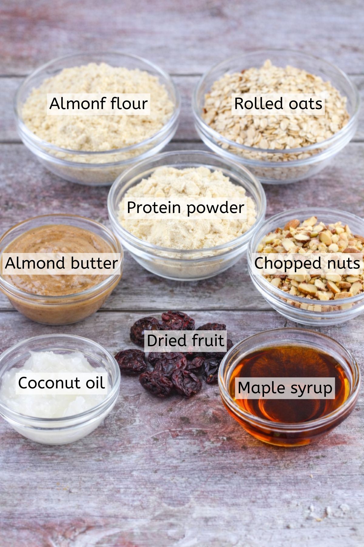 Multiple ingredients to make gluten-free protein bars in glass bowls with text over top.