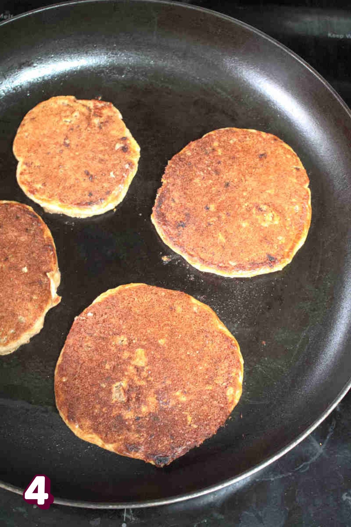 Almond flour protein pancakes being cooked in a black pan.
