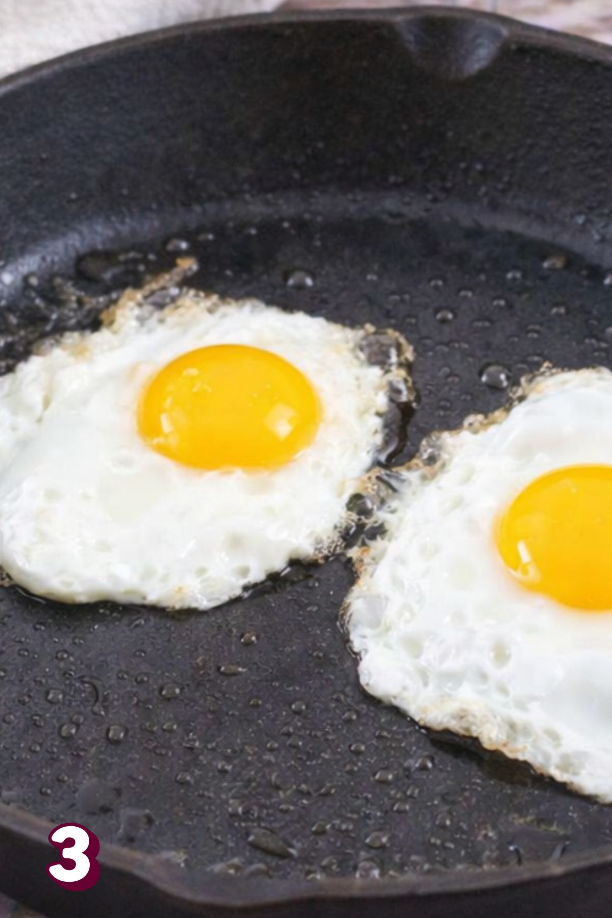 Eggs being cooked in a cast iron pan.