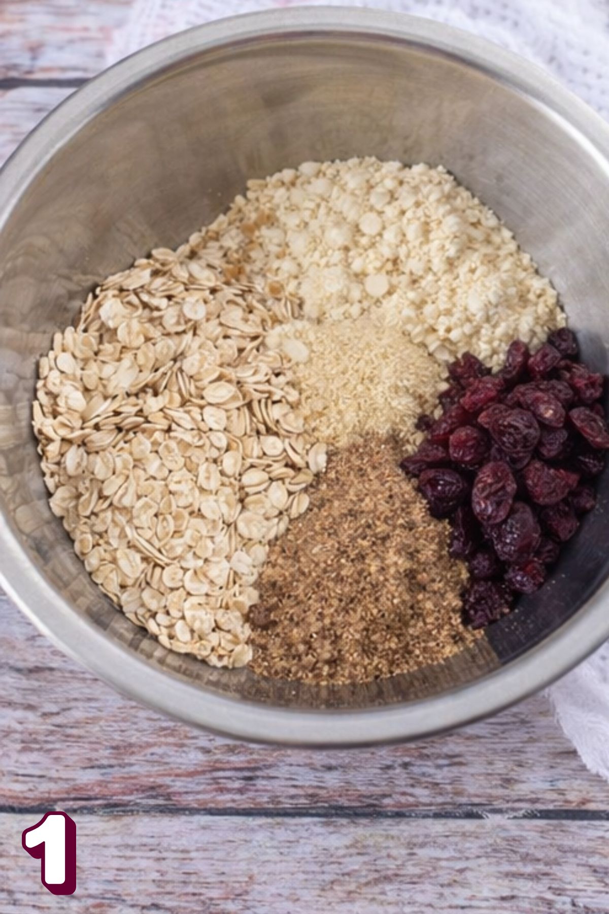 Steel bowl with almond flour, flax, oats, and dried cranberries.
