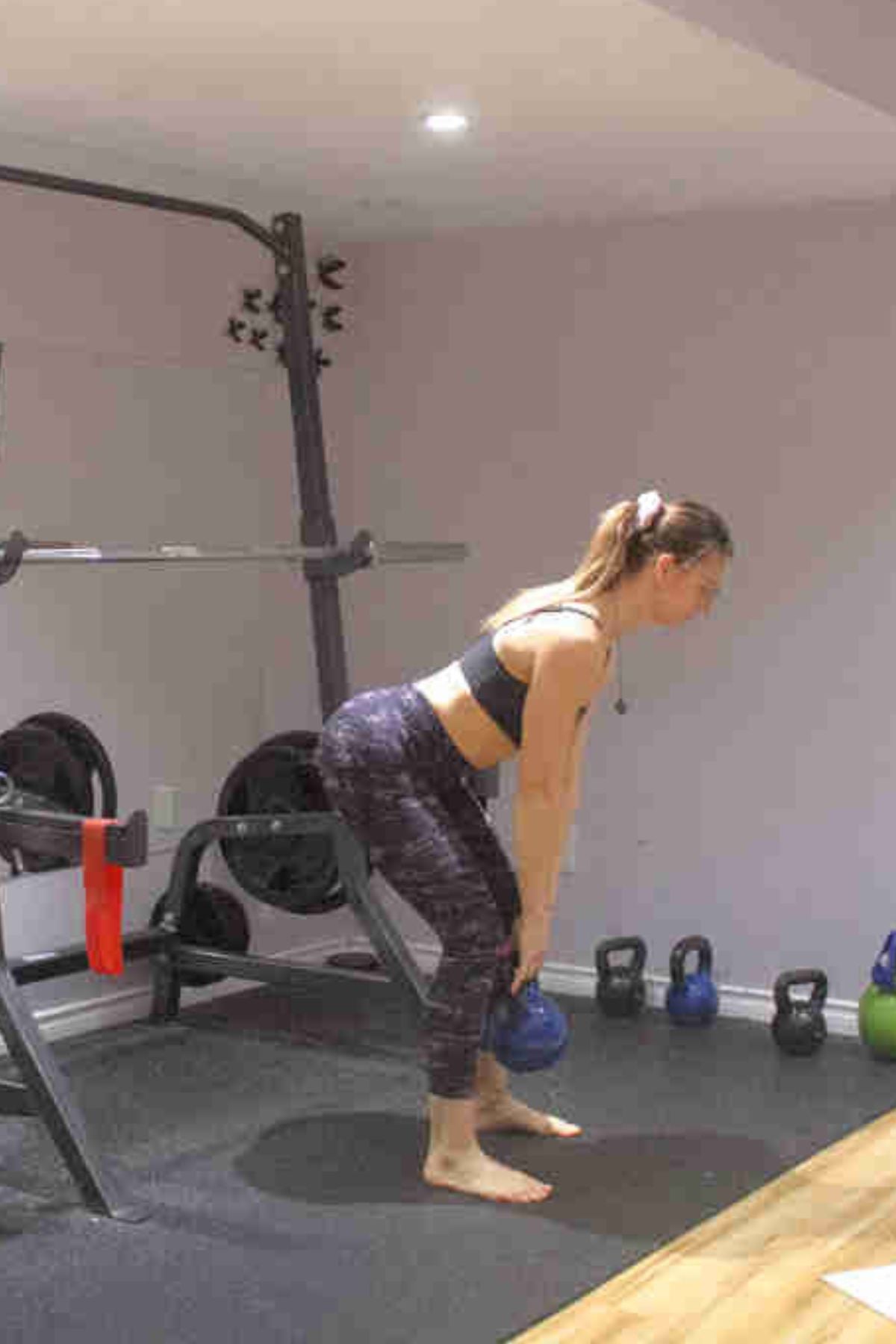 Woman performing a romanian deadlift with a kettlebell.