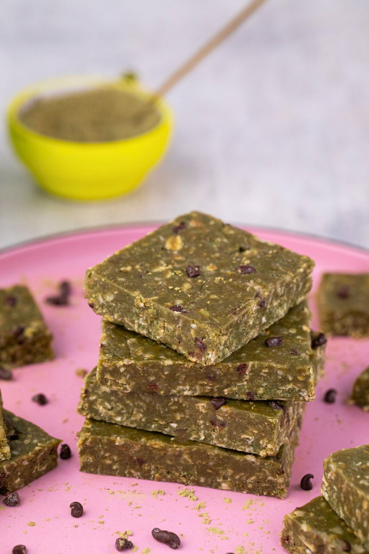 Four matcha protein bars stacked on a pink plate.