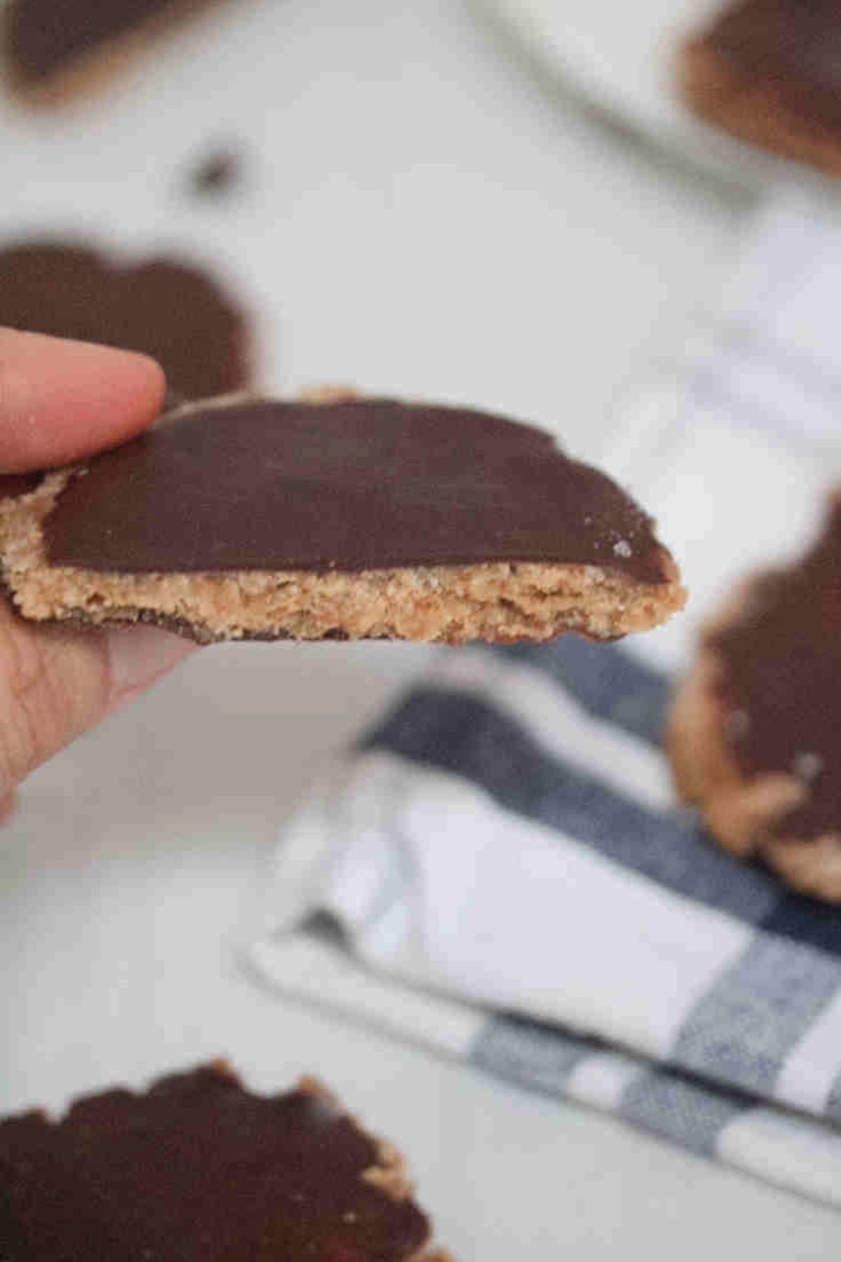 Fingers holding up a chocolate covered protein thin mint cookie broken in half.