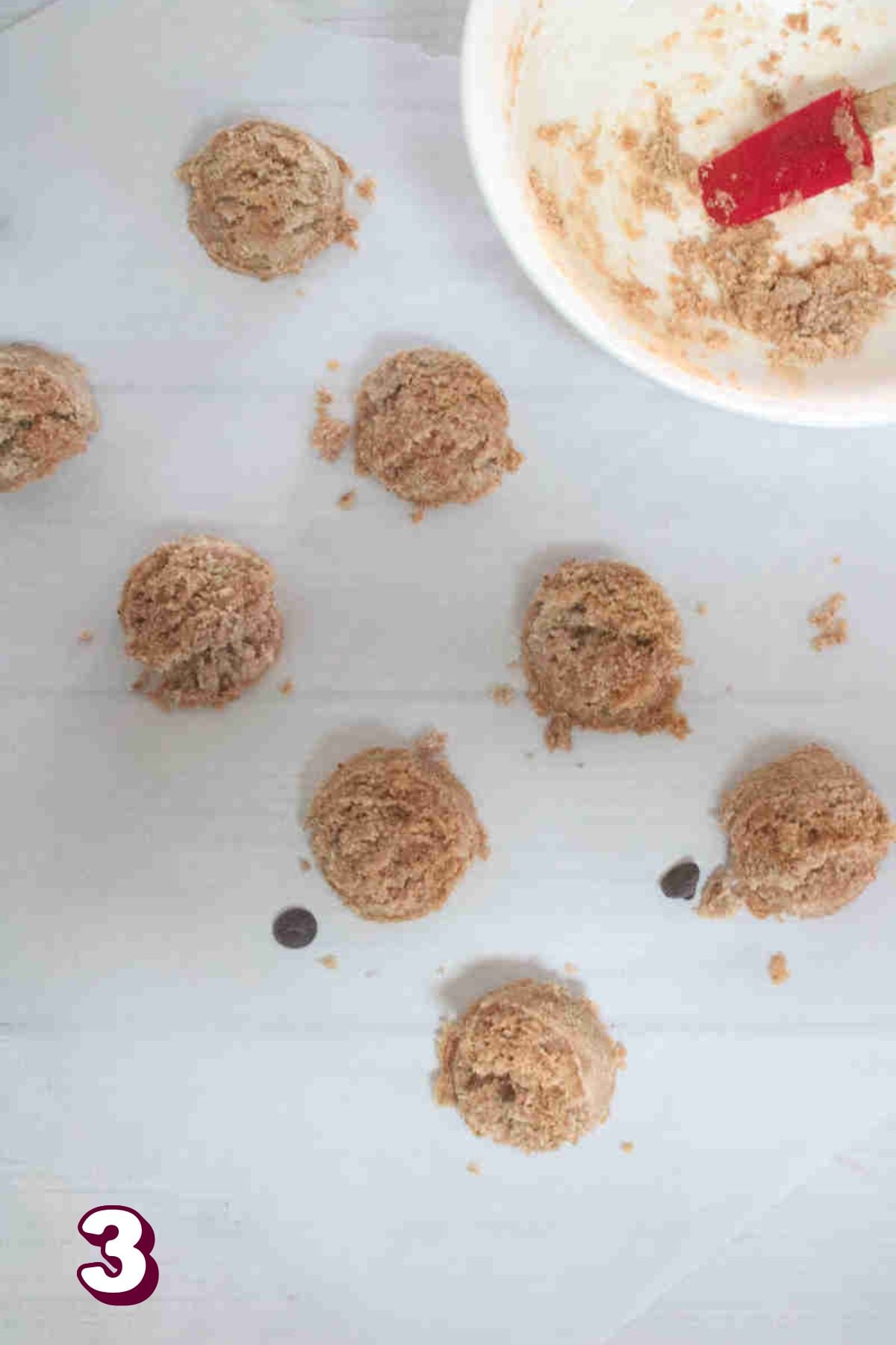 Raw cookie dough balls on parchment paper.