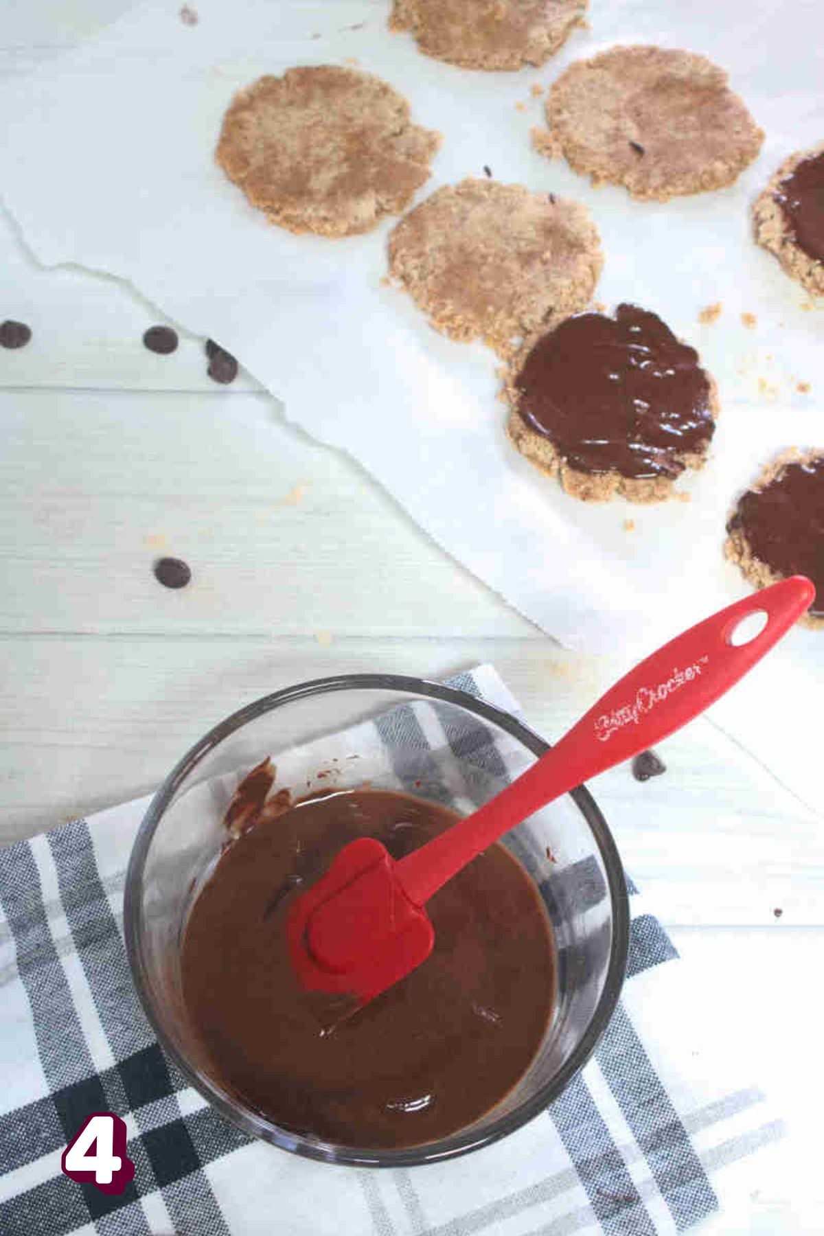 Beef protein cookies on parchment paper being painted with chocolate.