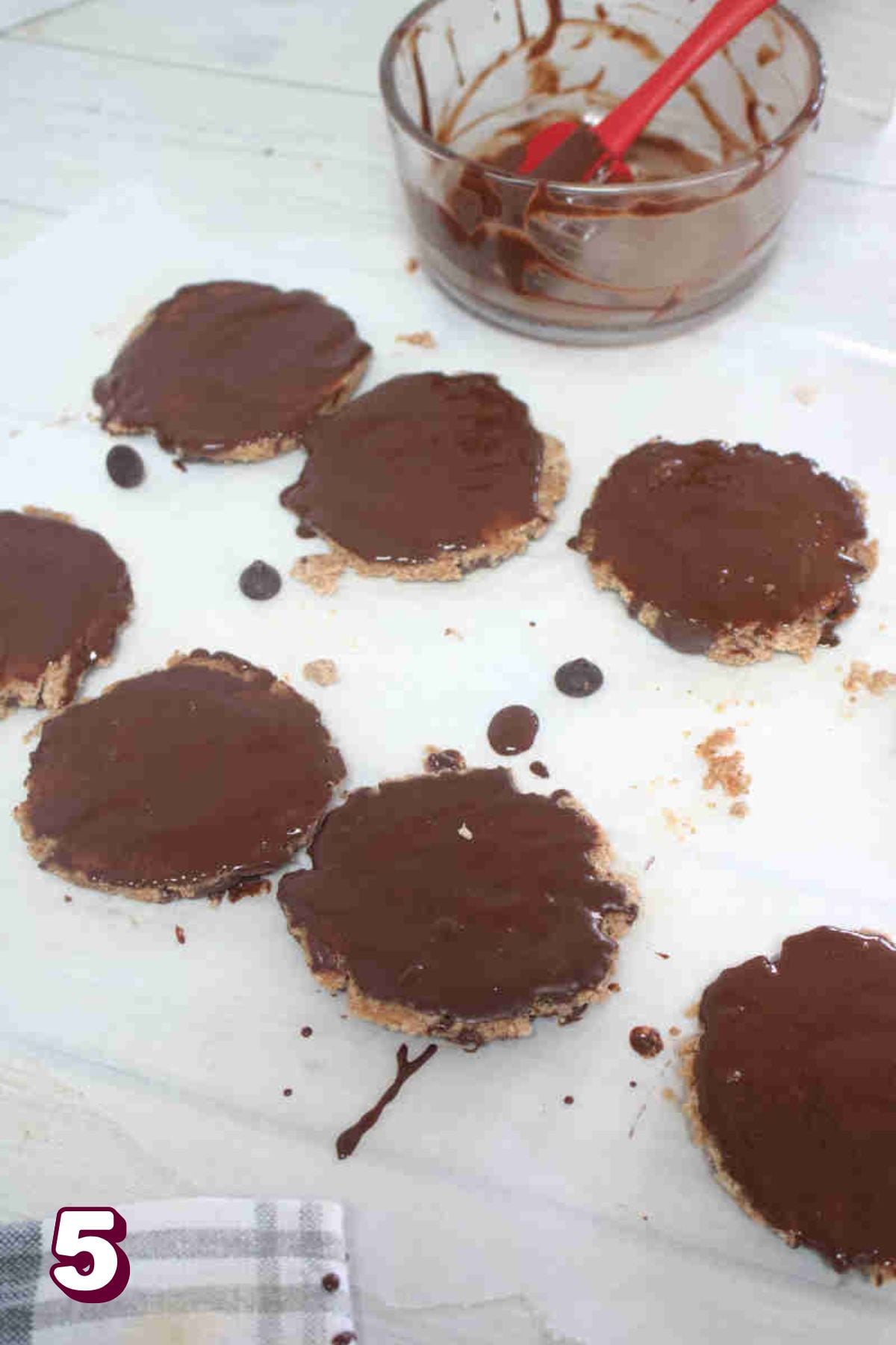 Beef protein cookies on parchment paper being painted with chocolate.