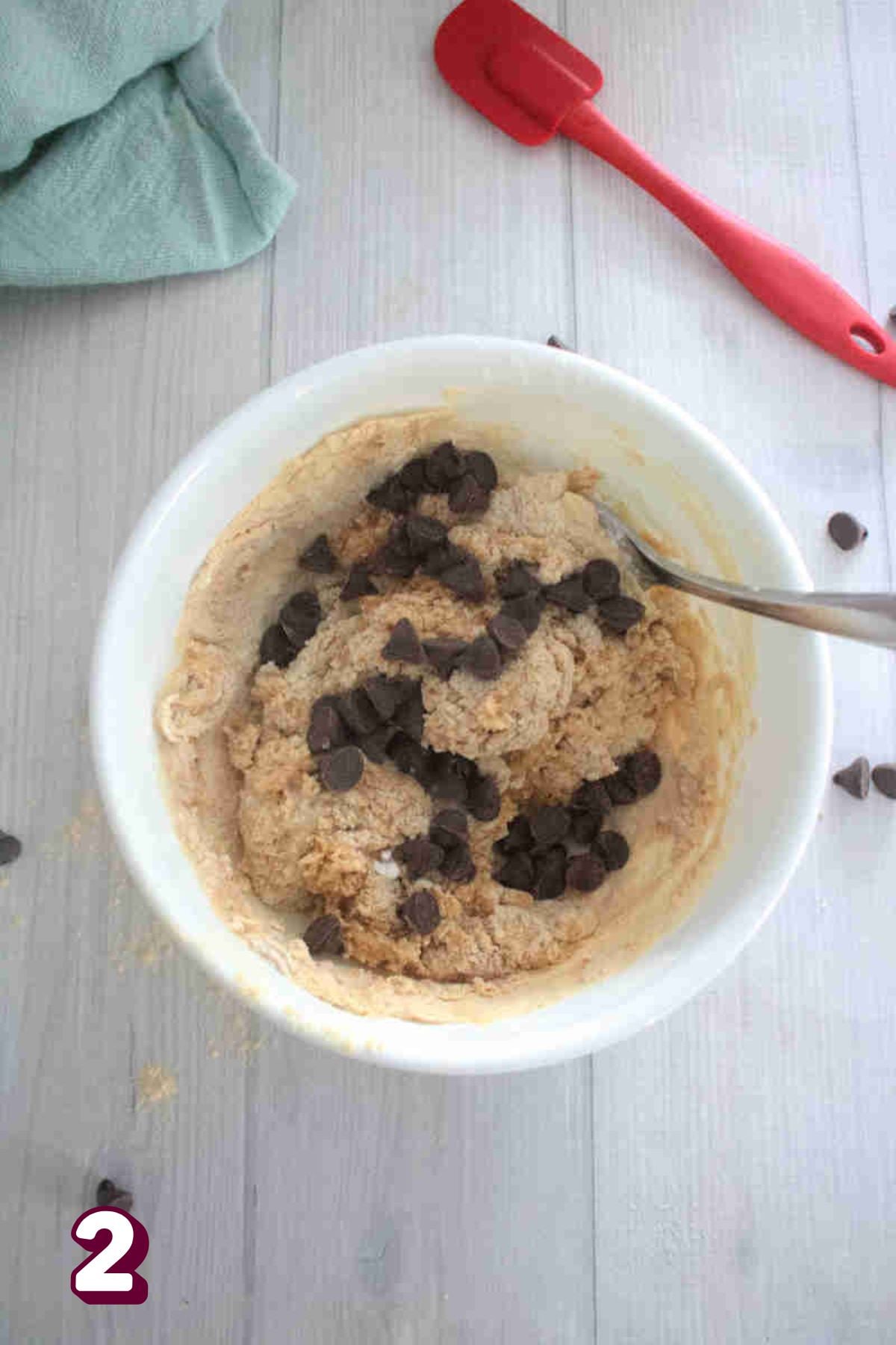 White bowl with protein powder, almond flour, coconut milk, and chocolate chips in it.