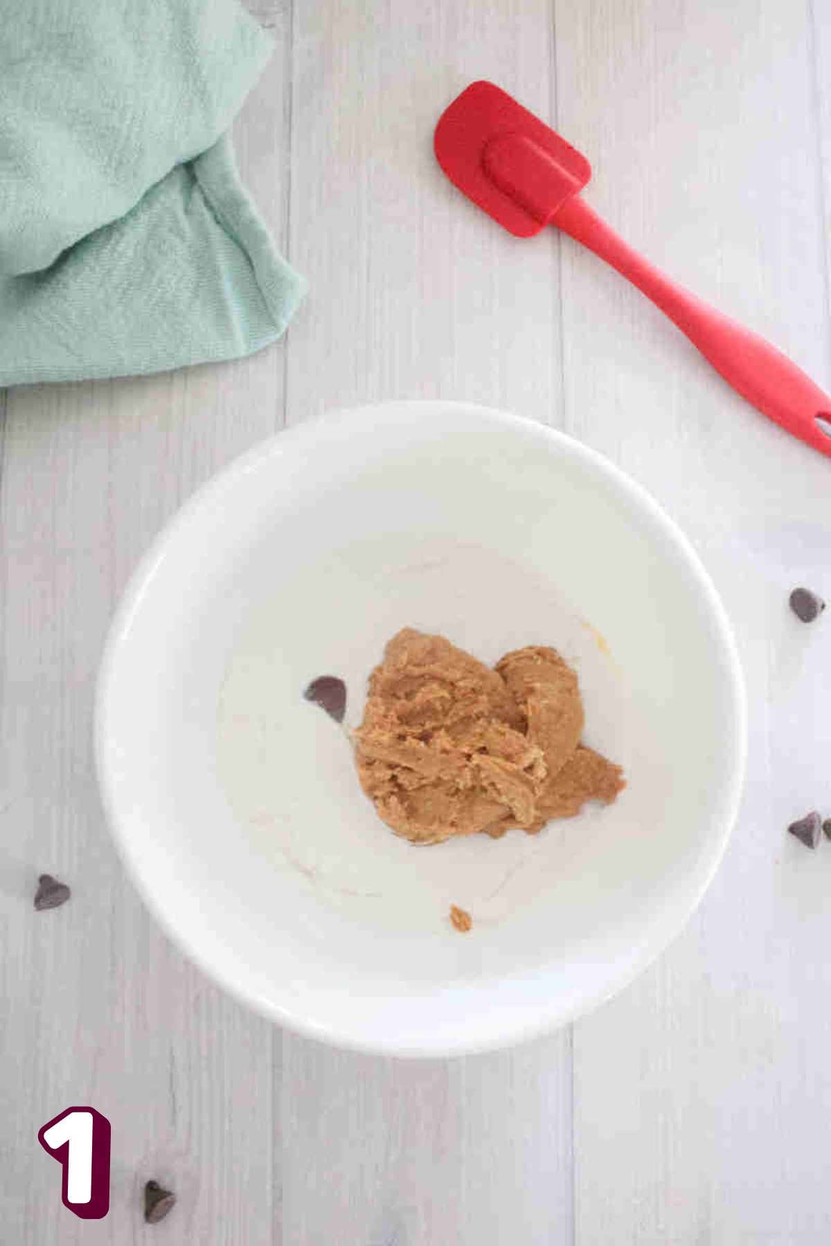 White bowl with peanut butter and coconut milk in it.