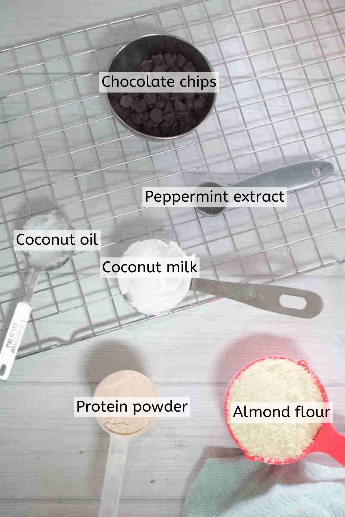 Ingredients like protein powder, chocolate chips, coconut milk, and more in measuring cups with text labels over the top.