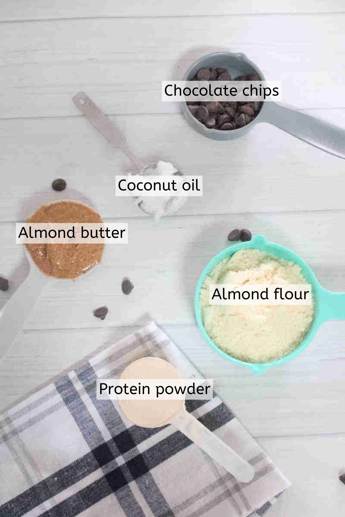 Ingredients like protein powder, chocolate chips, coconut milk, and more in measuring cups with text labels over the top.