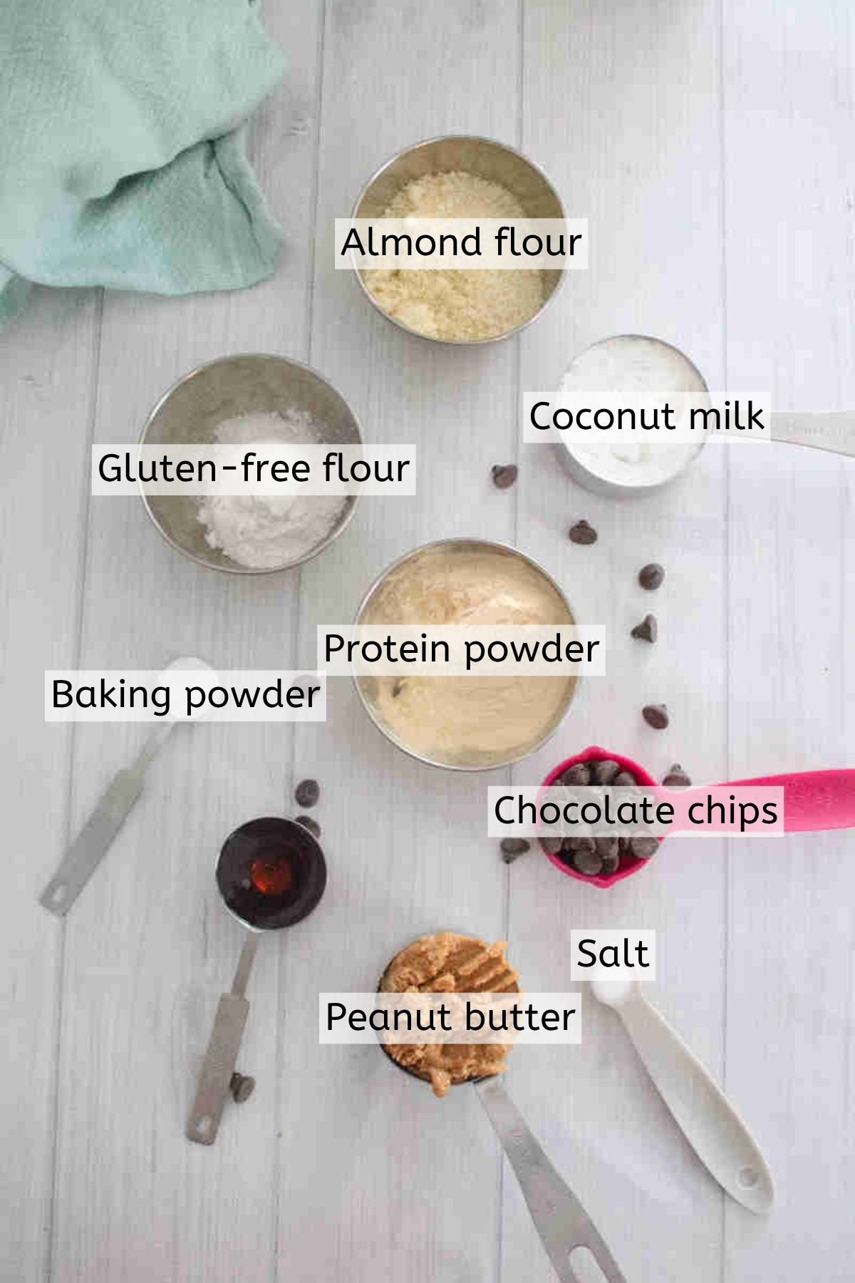 Ingredients like protein powder, chocolate chips, coconut milk, and more in measuring cups with text labels over the top.