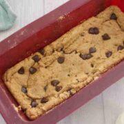 Protein blondies in a red silicone loaf pan with chocolate chips on top.