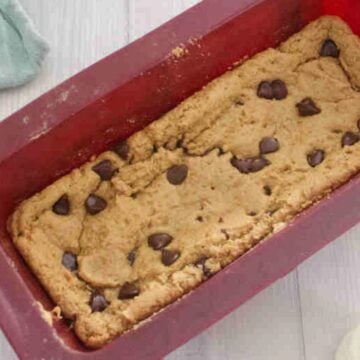 Protein blondies in a red silicone loaf pan with chocolate chips on top.