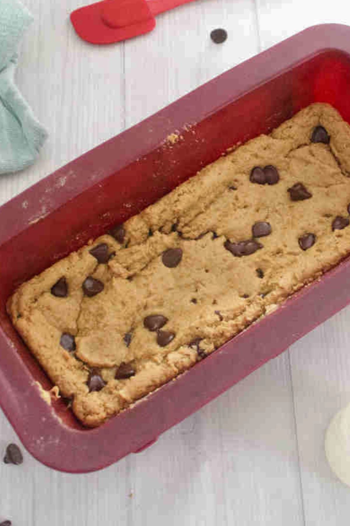 Protein blondies in a red silicone loaf pan with chocolate chips on top.