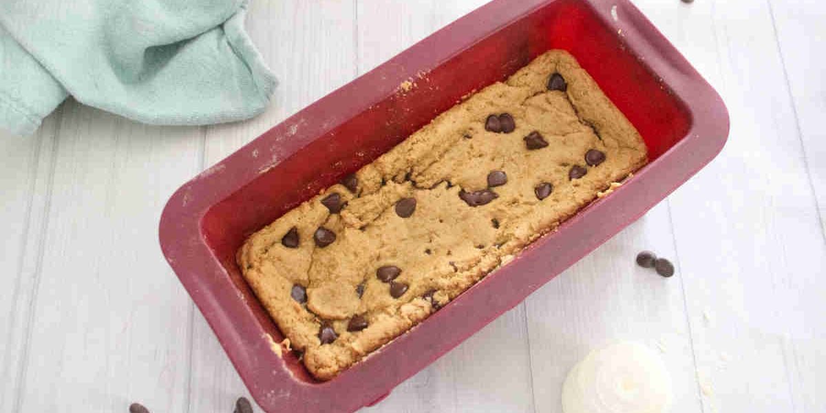 Protein blondies in a red silicone loaf pan with chocolate chips on top.