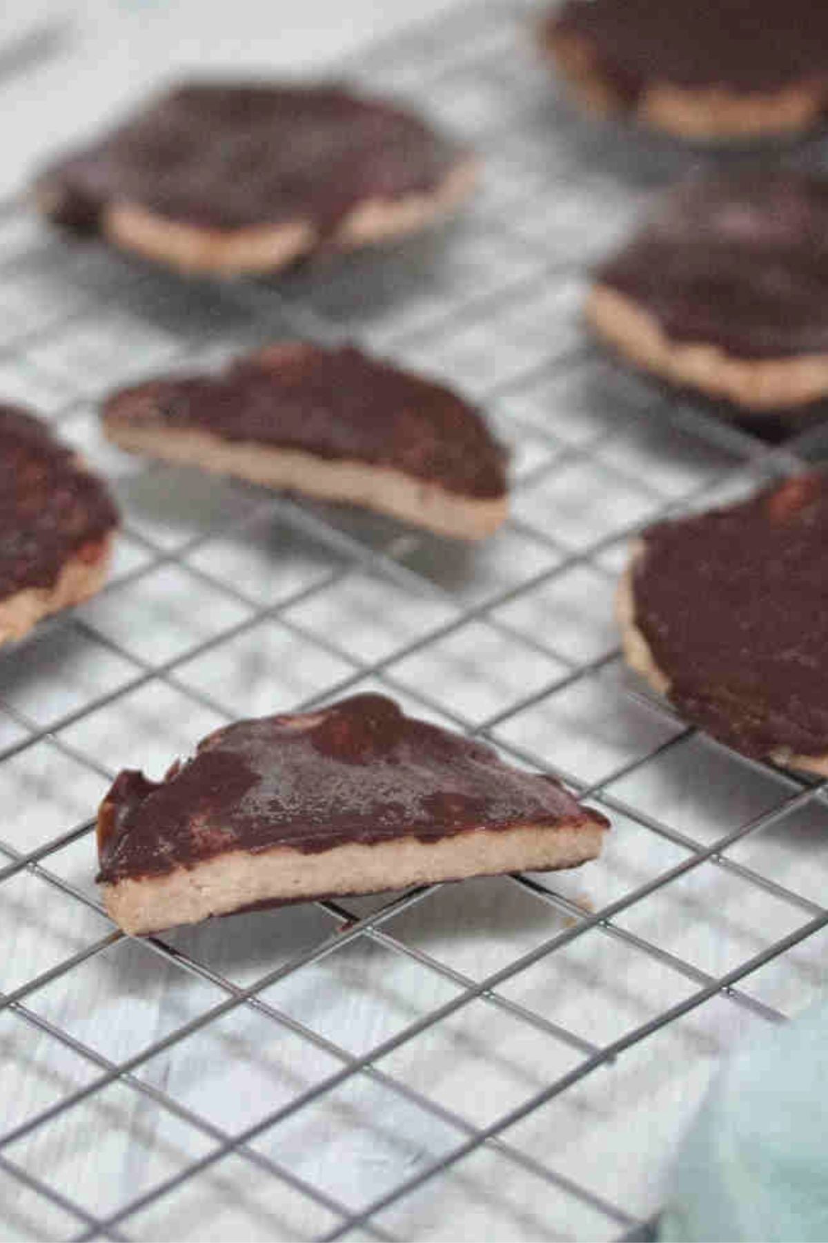 Chocolate coated protein thin mint cookies on a wire rack with some cookies sliced in half.