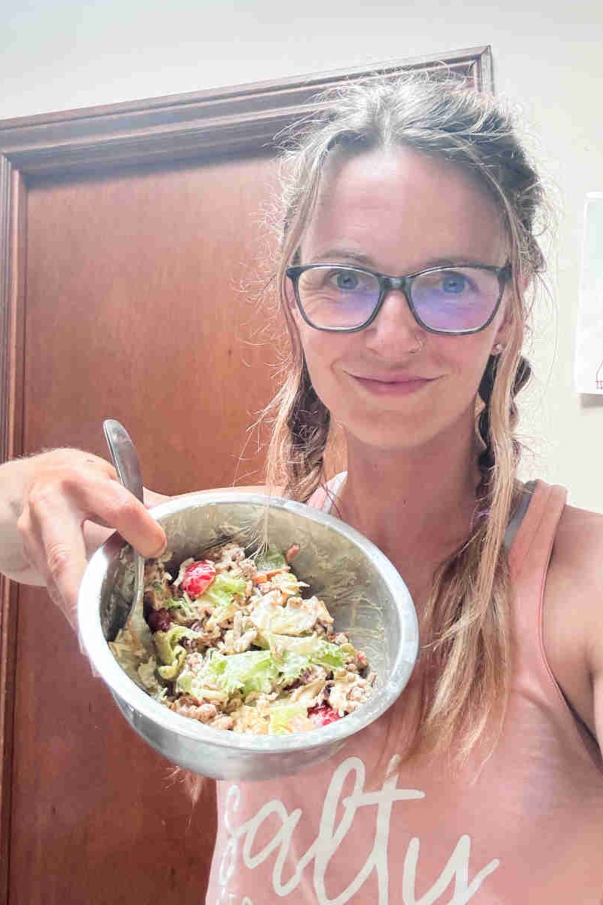 Woman holding up a bowl with a lunchtime protein salad.