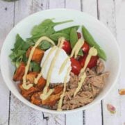 White bowl with ground meat, yogurt, veggies, and sweet ptoatoes.