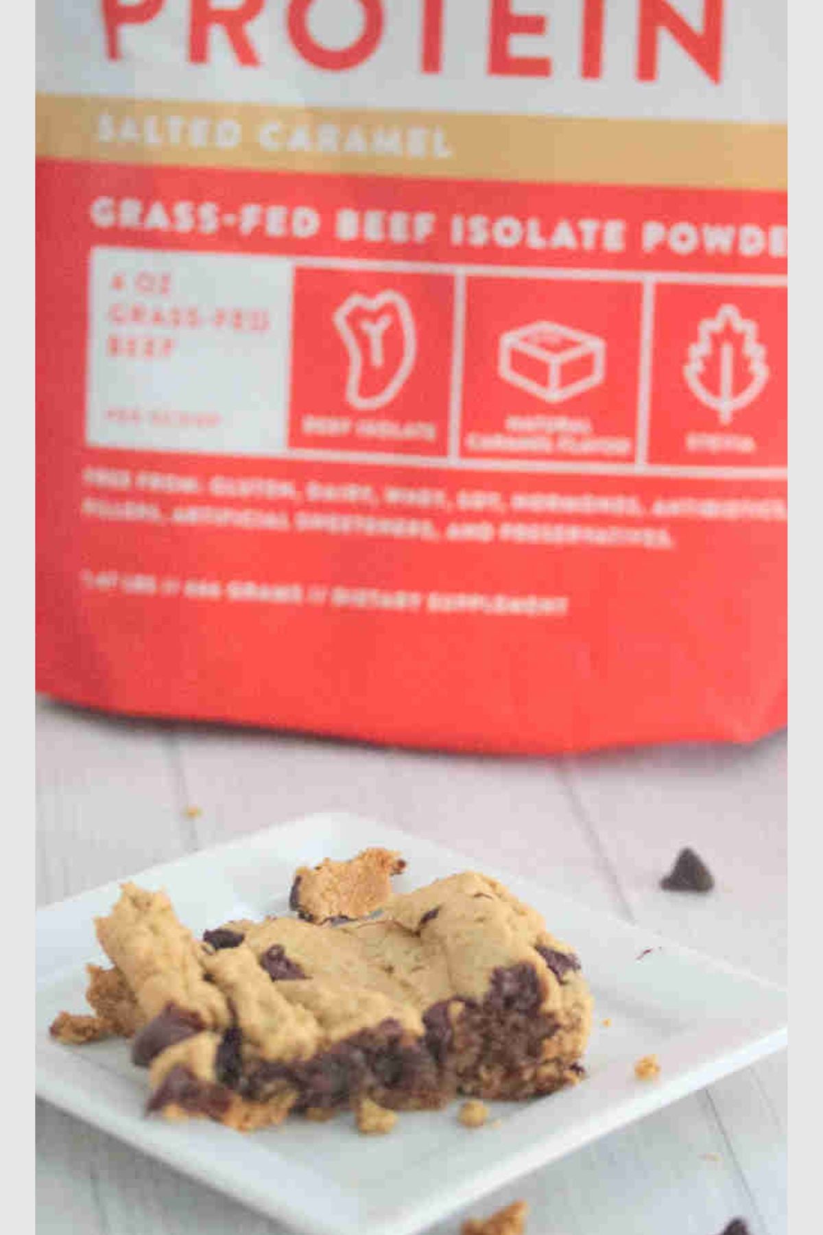 Protein blondie on a white plate with a bag of protein powder behind it.