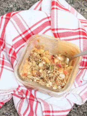 Protein apple crumble with oat topped in a single serve ramekin on top of a red linen.