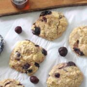 High-protien muffin tops with cherries on parchment paper with cherries around them.