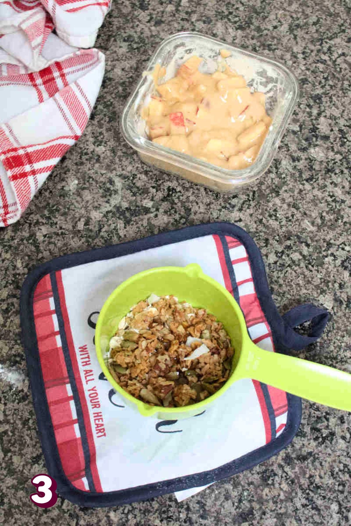Green measuring cup with homemade crumble topping and an apple and protein powder mixture behind it in a ramekin.