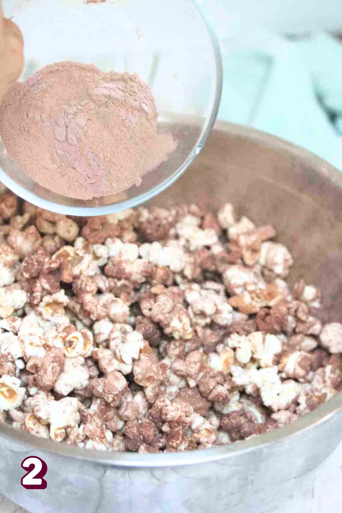 Protein powder being poured onto a bowl of popcorn.
